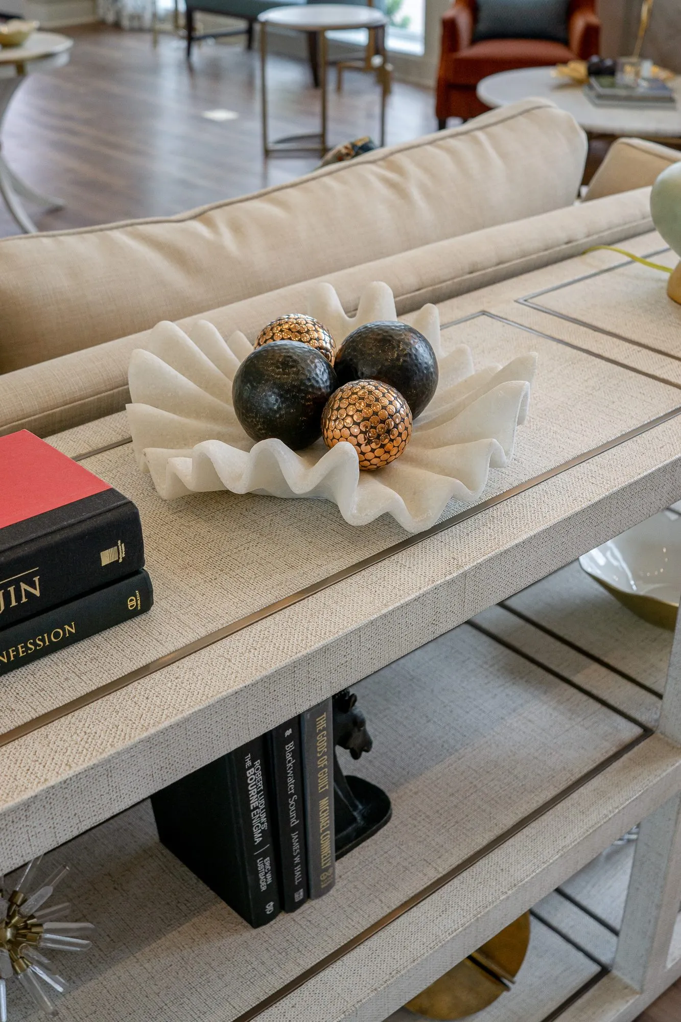Senior living interior detail: linen-wrapped console top with a shell bowl of black and copper spheres and stacked books