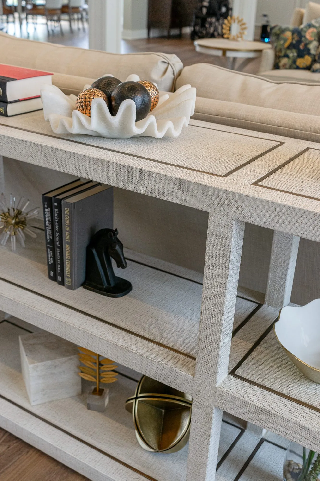 Senior living interior detail: linen-wrapped console shelves with a shell bowl of spheres, black books and a horse bookend