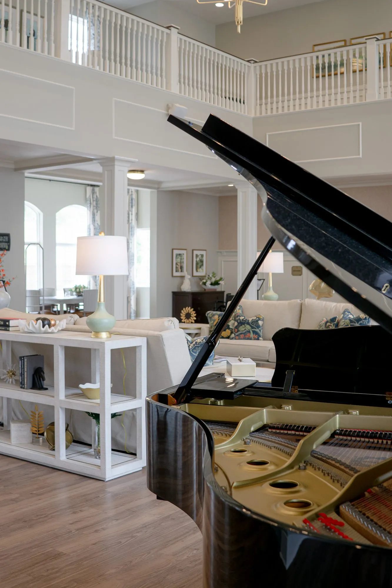 Senior living great room with an open grand piano in the foreground, white shelving and the balcony railing beyond
