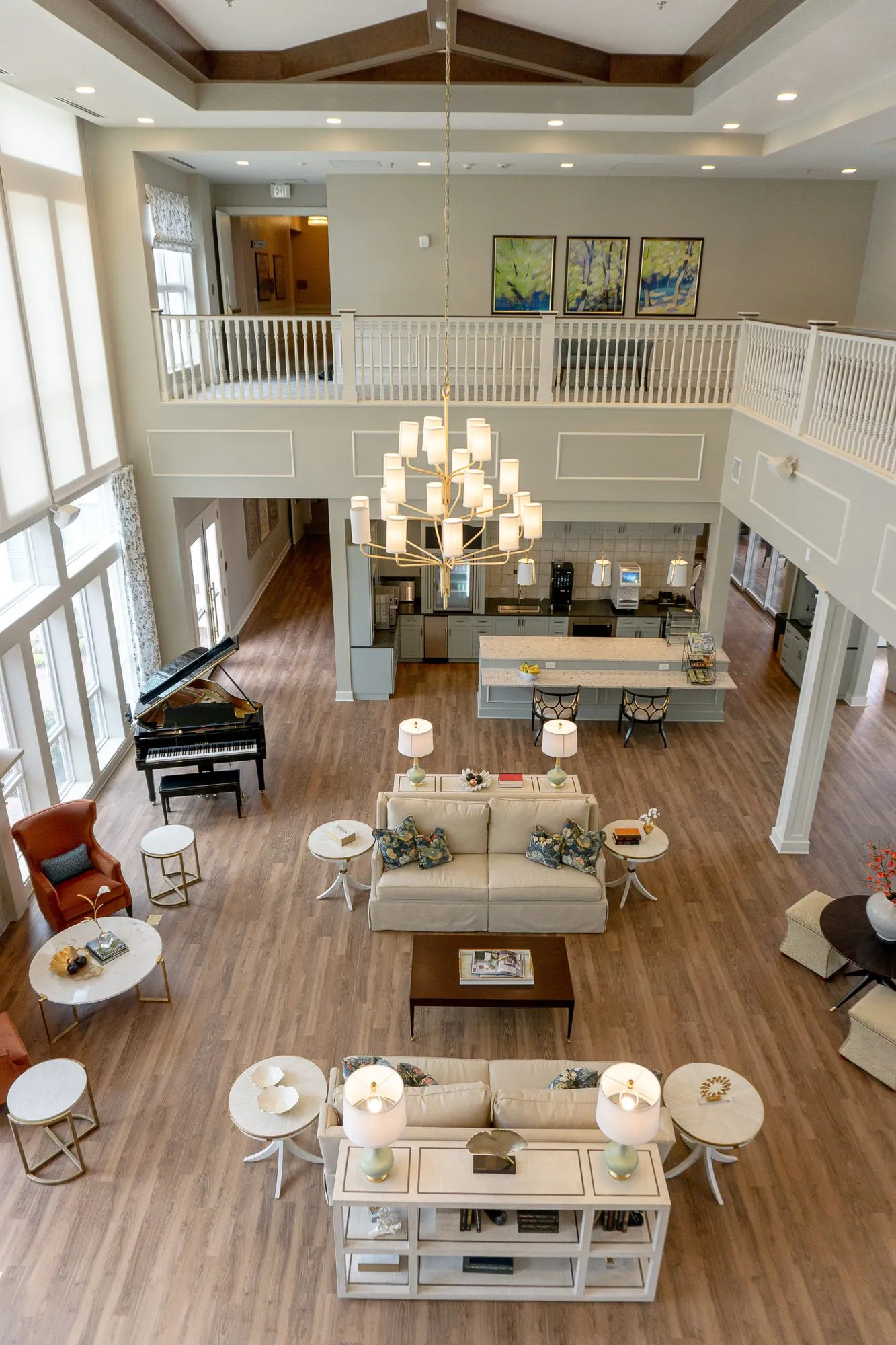 Senior living great room from the balcony, sofas and consoles leading to a grand piano and the kitchen beyond