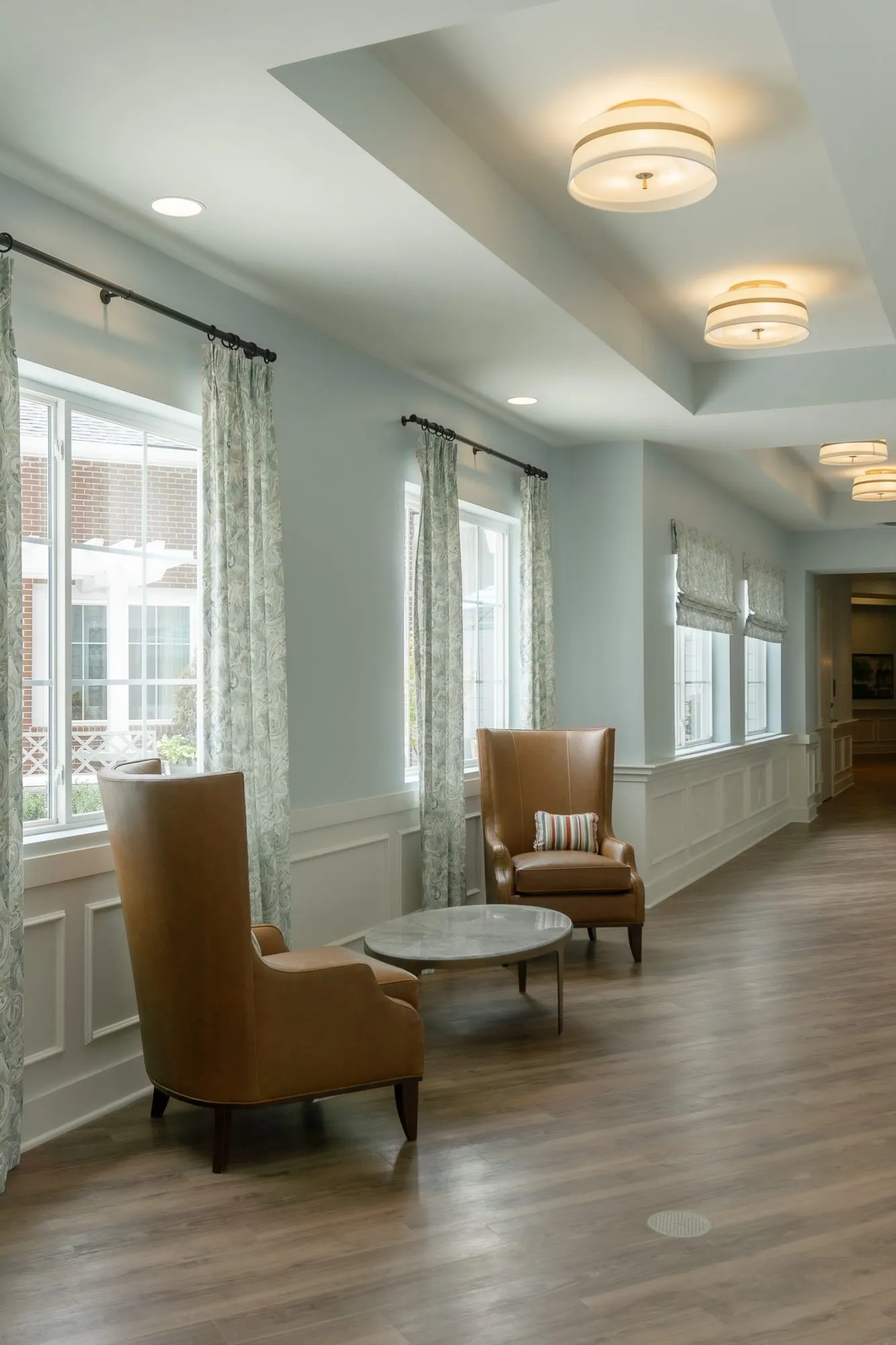 Senior living window lounge with a cognac wing chair and a leather armchair around a round table