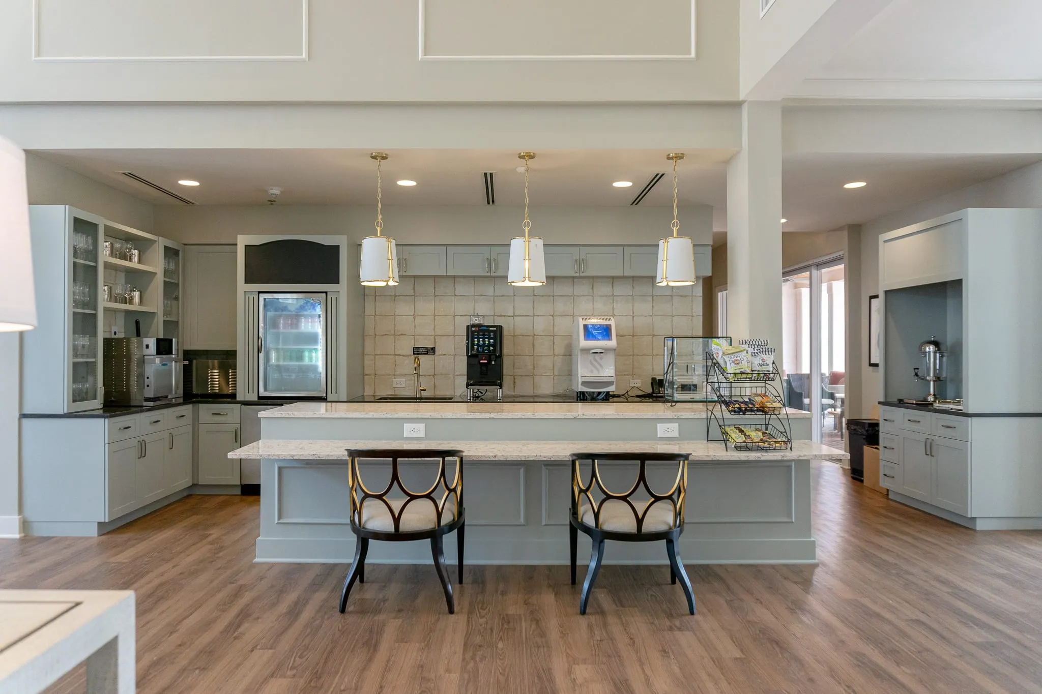 Senior living bistro counter with pale blue cabinetry and pendant lights above two upholstered stools