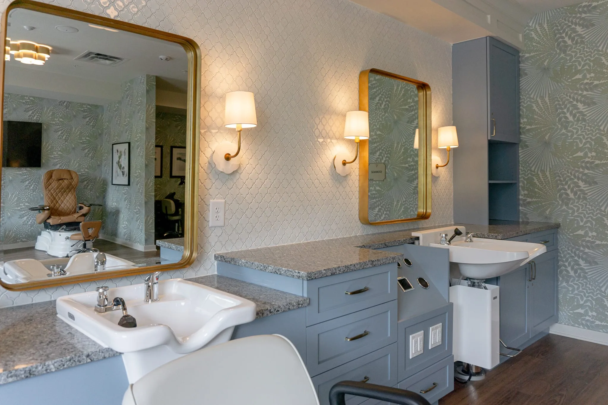 Senior living salon with shampoo bowls and gilt mirrors against botanical wallpaper and grey cabinetry